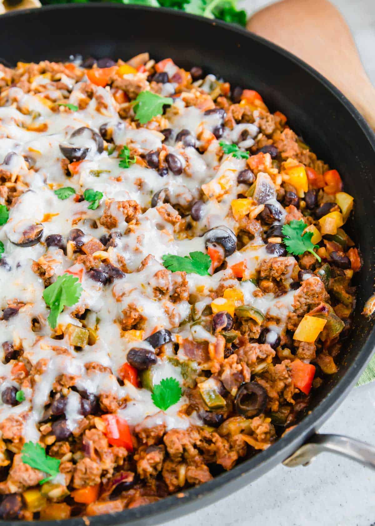 Ground beef Mexican recipe with beans, rice, peppers and melted cheese.