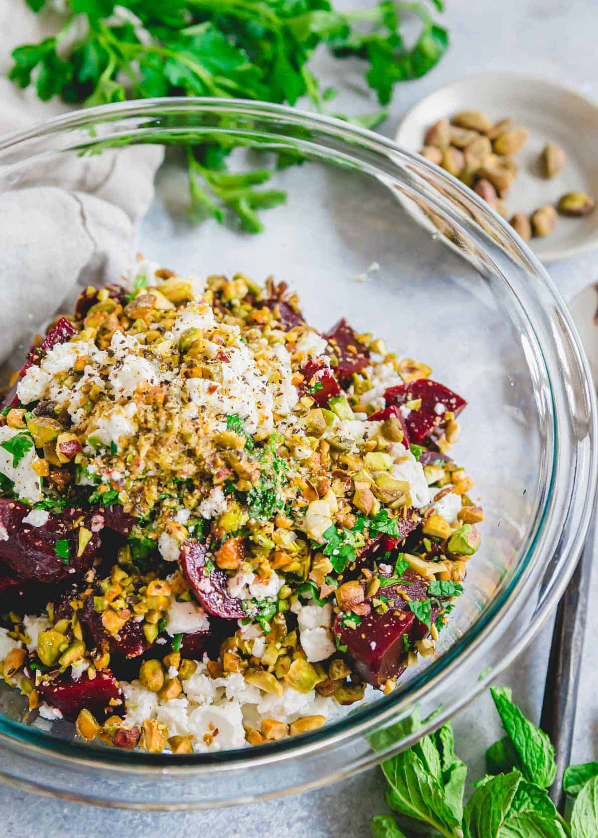 Tossing together the ingredients for a beet and feta cheese salad in a large glass bowl.