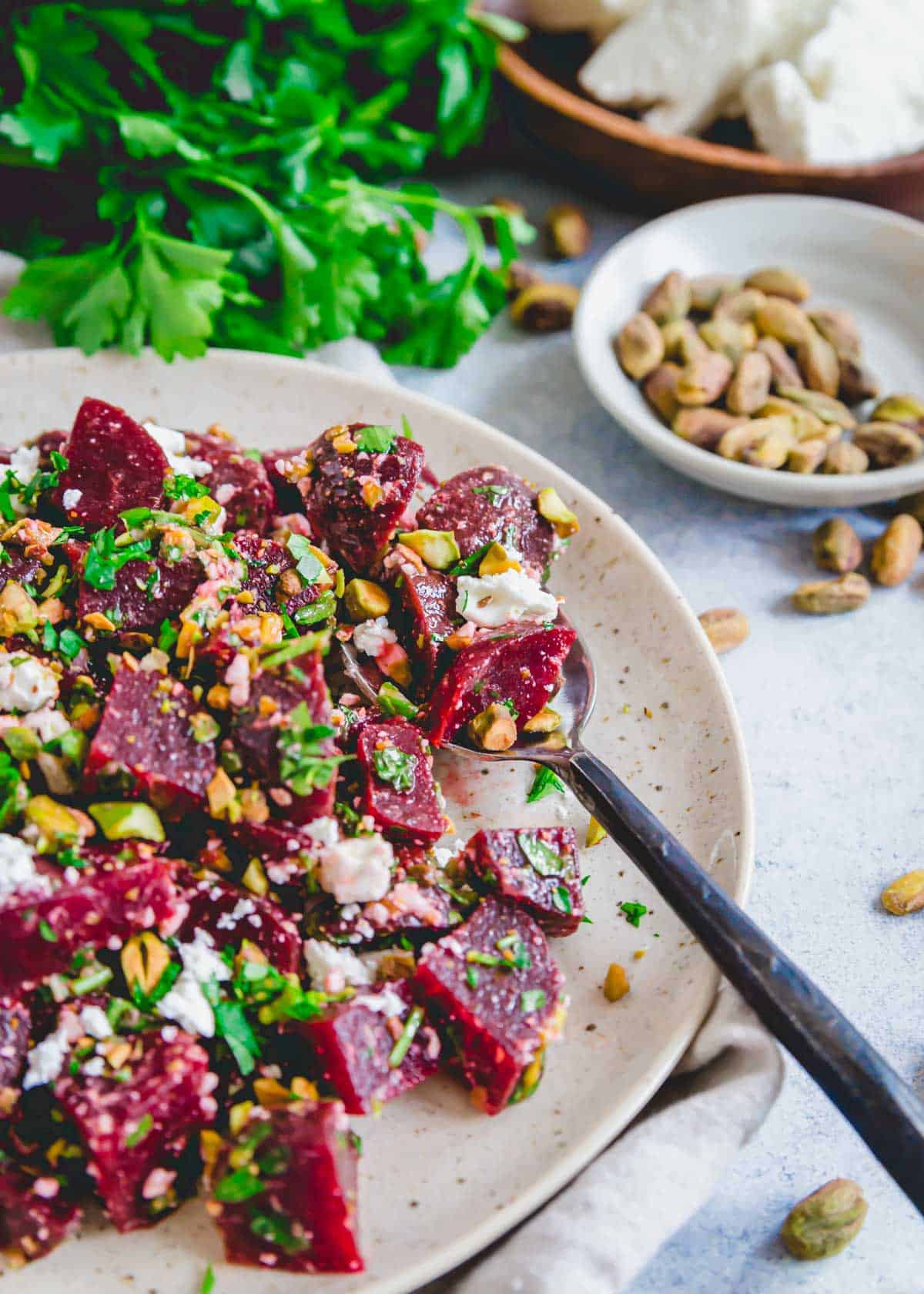 Beet salad with feta dressed with a lemon olive oil vinaigrette served on a plate with a black spoon.