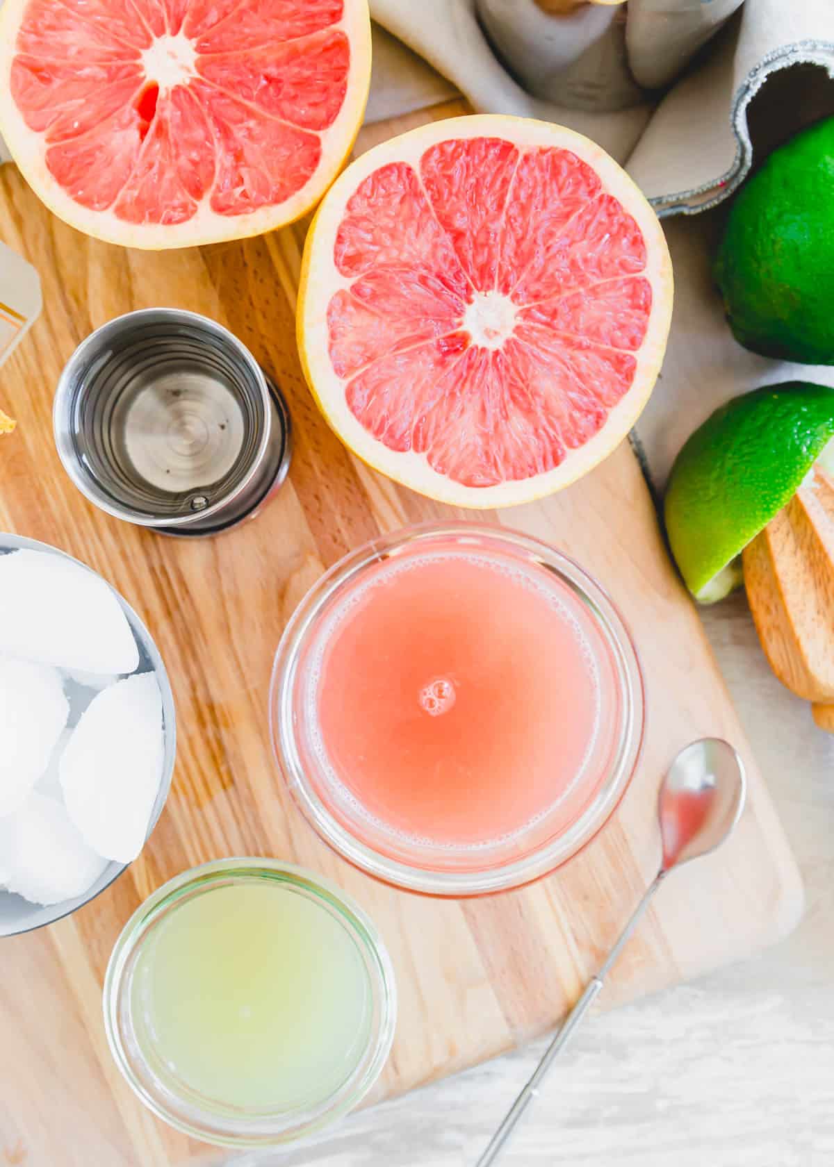 Fresh grapefruit juice, lime juice and ice cubes on a cutting board.