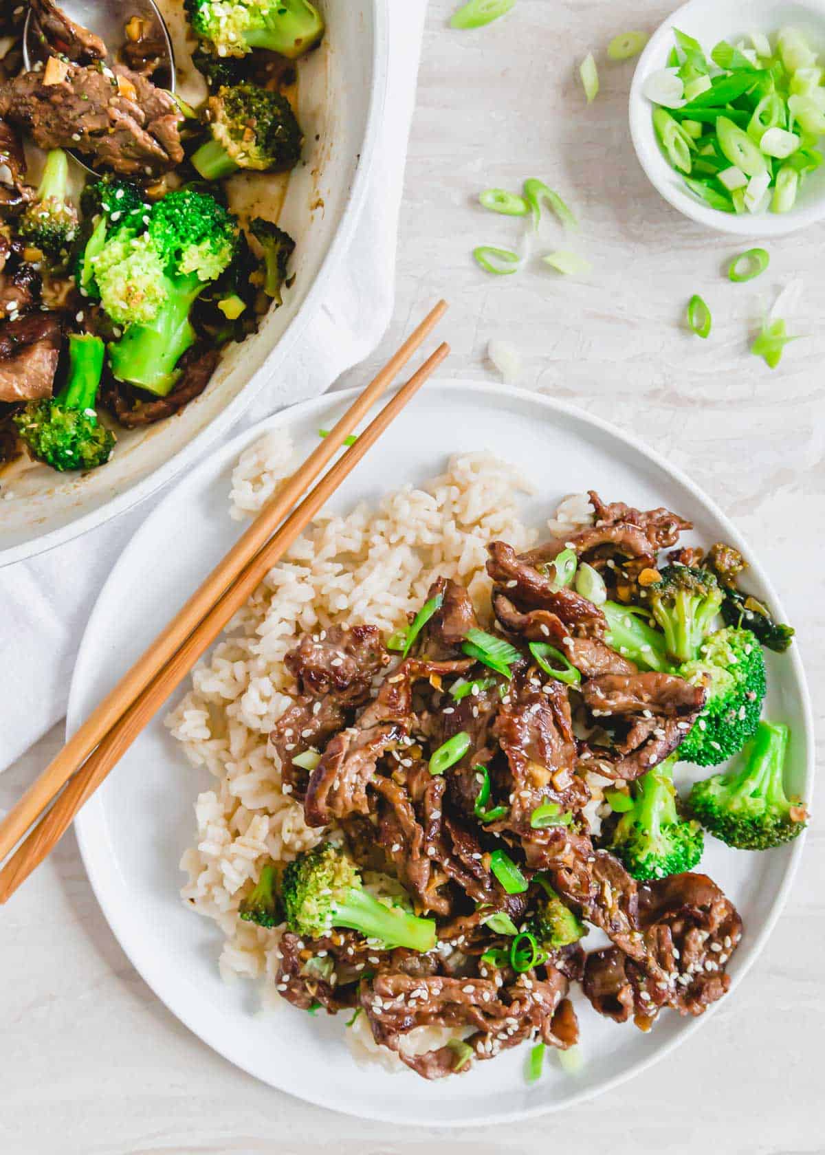 Mongolian shaved beef and broccoli recipe served with rice on a plate with chopsticks.