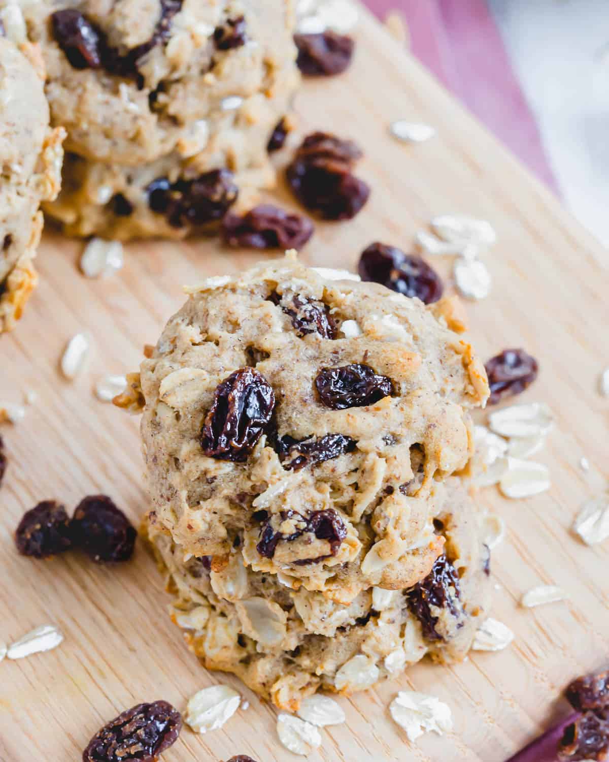 Soft and chewy gluten-free vegan raisin oatmeal cookies on a wooden board.