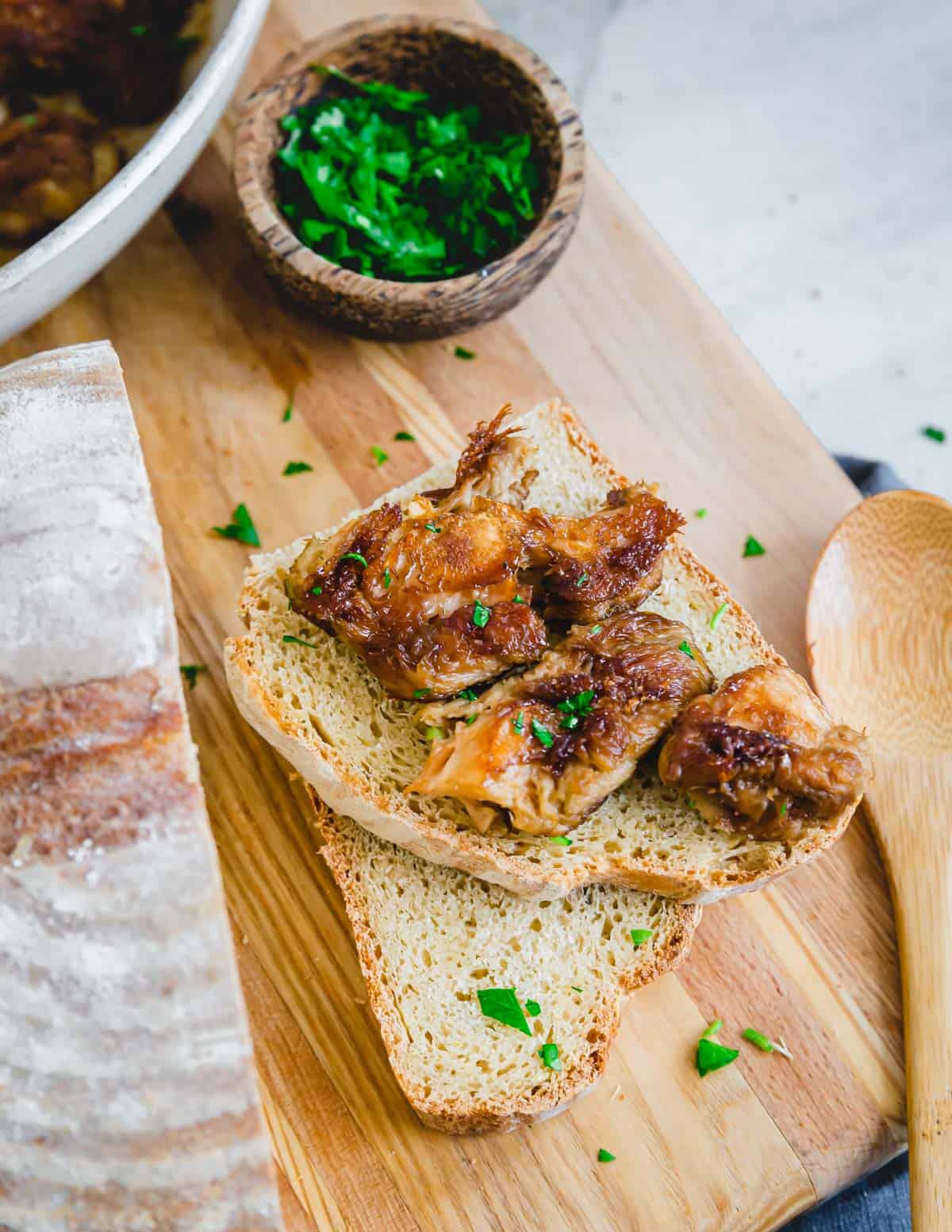 Golden caramelized lion's mane mushrooms on top of a rustic piece of bread on a cutting board.