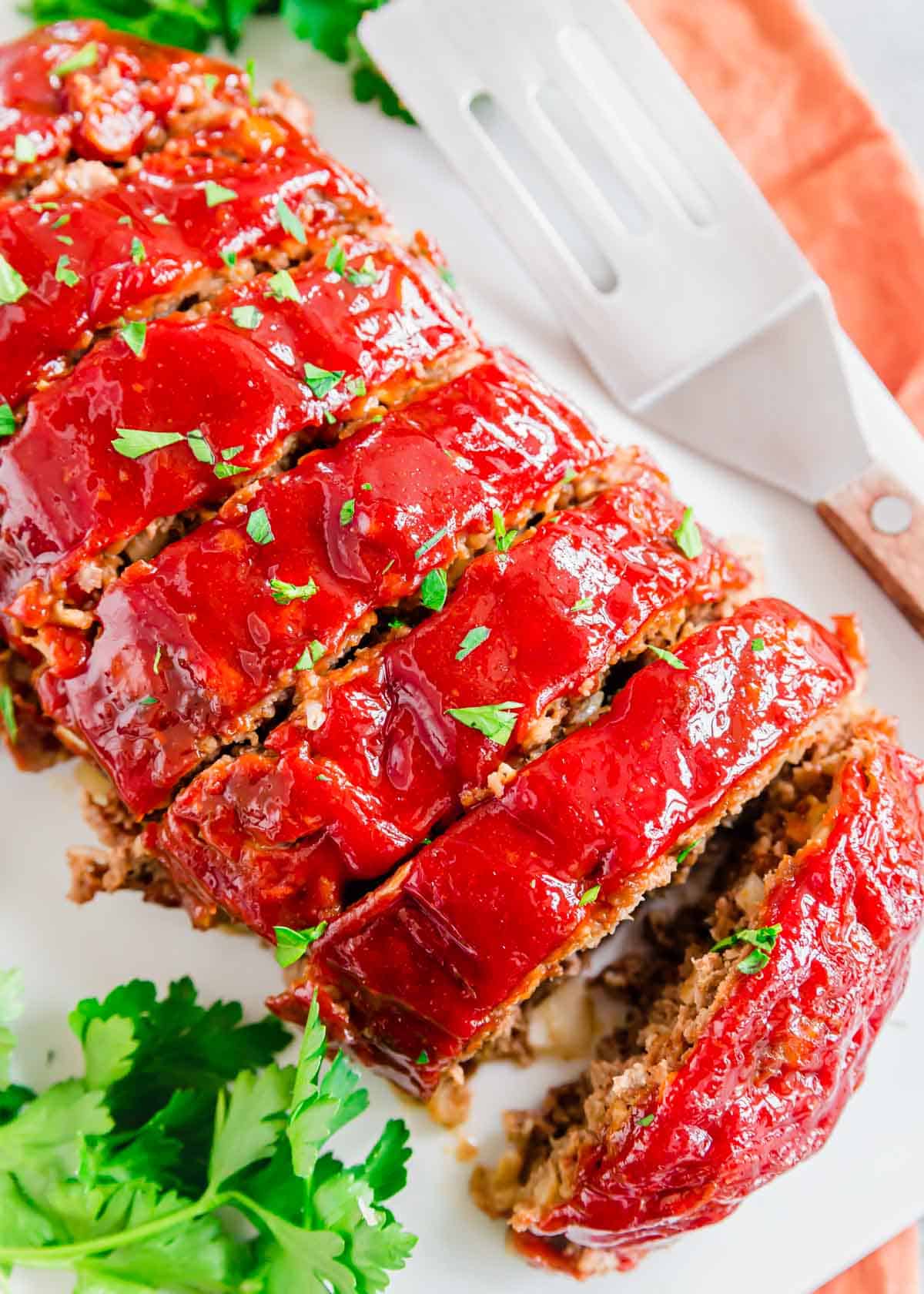 Close up of sliced bomb meatloaf recipe on a serving platter garnished with chopped parsley.