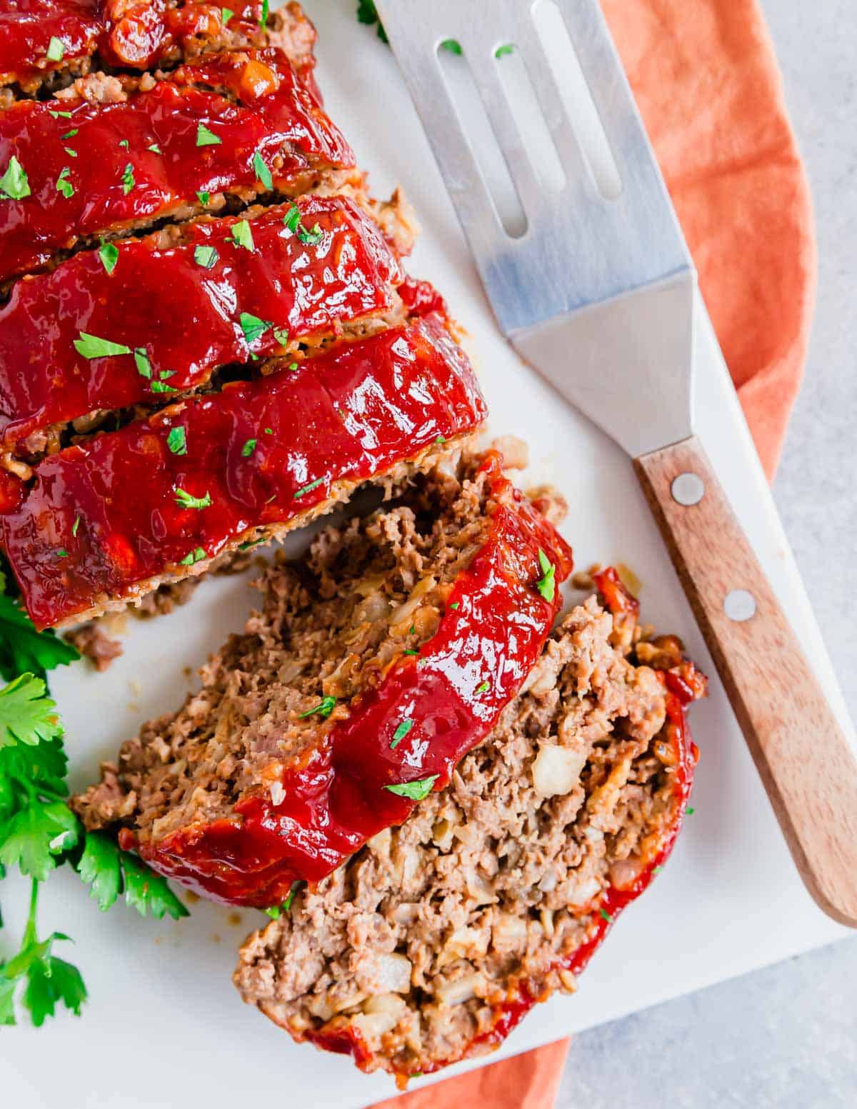 Two slices of glazed meatloaf showing the tender inside on a white plate.