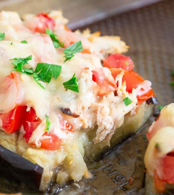 Cheesy chicken stuffed eggplant on a baking sheet.