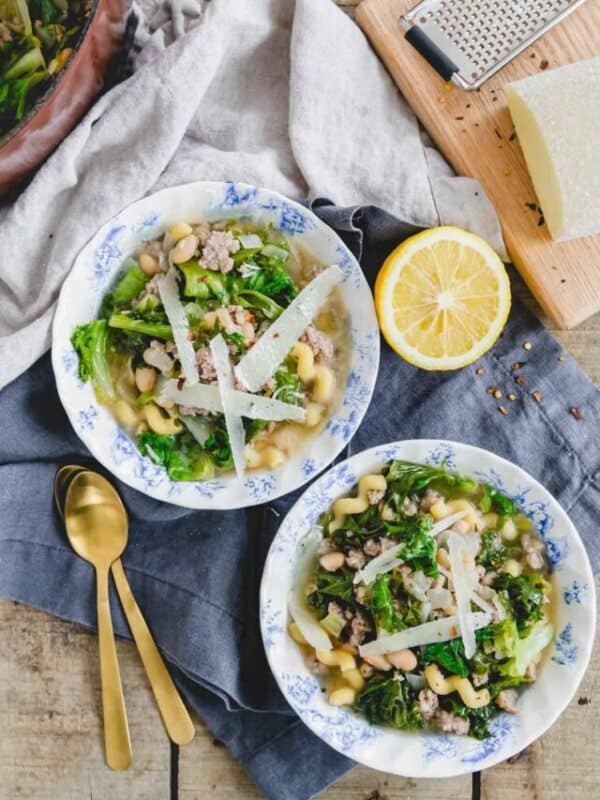 Two bowls of soup with vegetables and cheese.