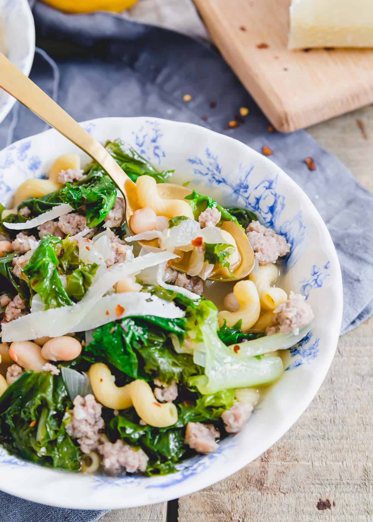 Spoonful of escarole and bean soup with sausage and cavatappi pasta.