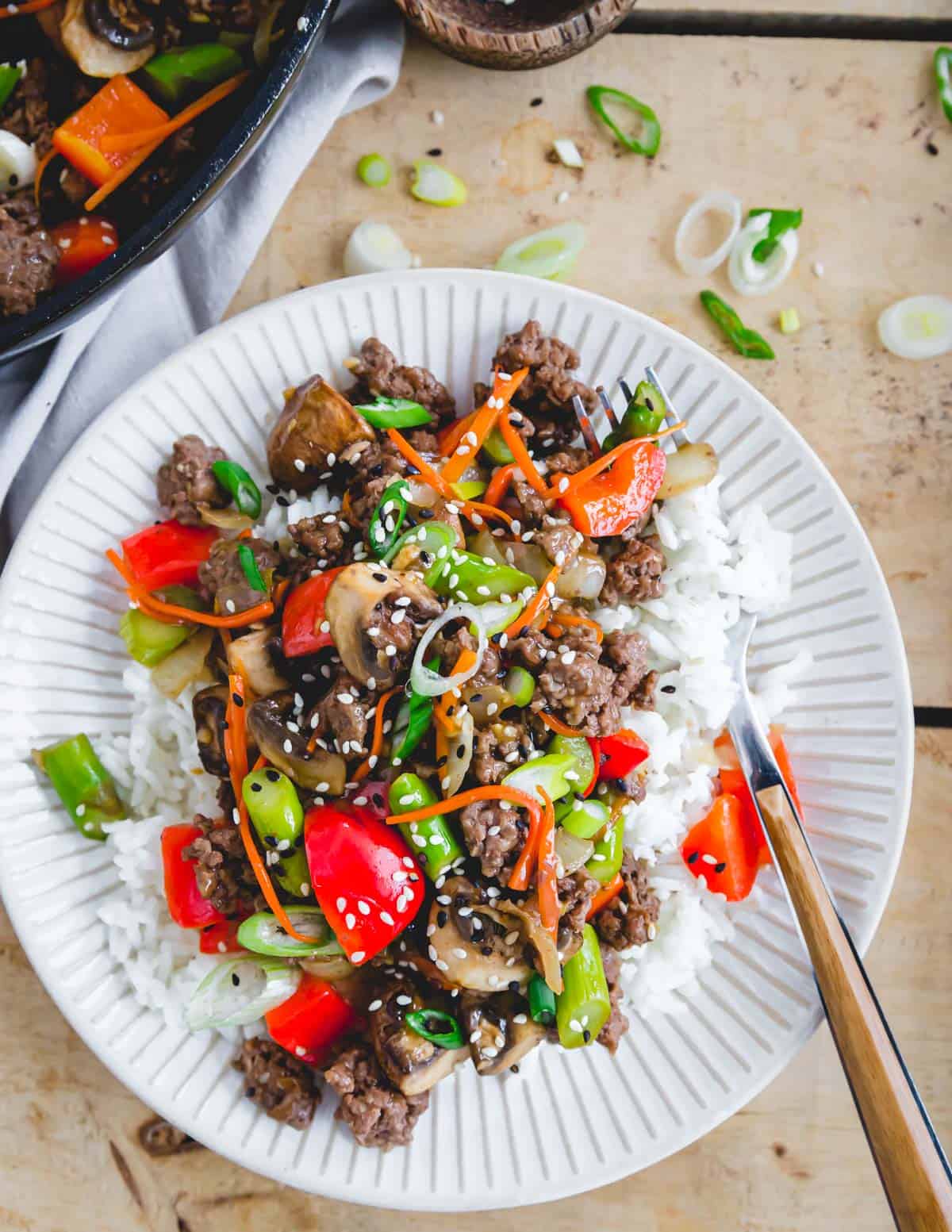 Easy ground beef stir fry recipe served over white rice on a plate with a fork.