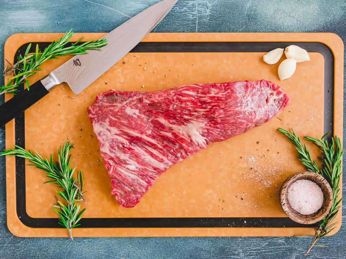 Raw "triangle steak" known as tri tip on a cutting board.