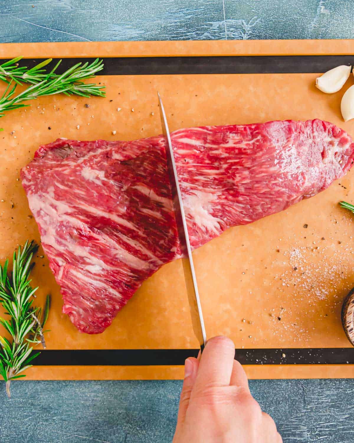 Knife demonstrating where to cut a tri tip steak in half in order to cut it properly against the grain.