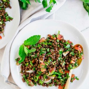 Lentil tabbouleh on a white plate with a gold spoon.