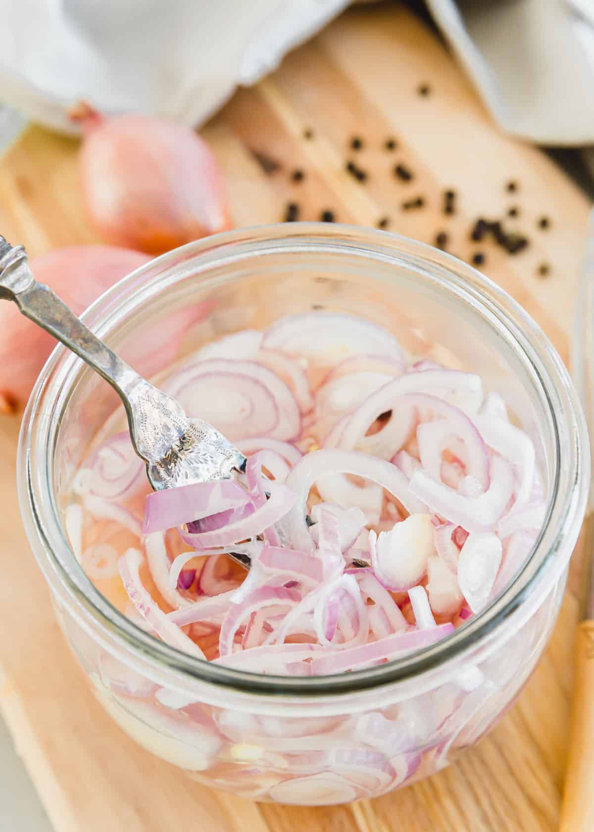 Pickled shallot recipe with peppercorns in a glass jar with a fork.