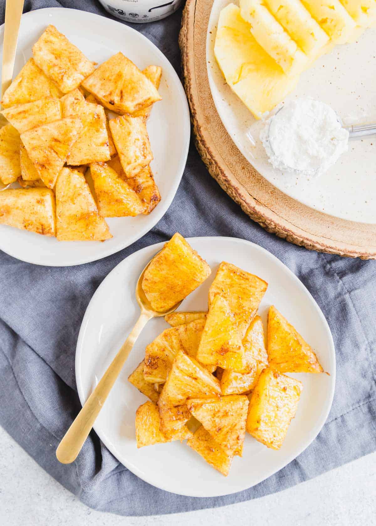 Air fried pineapple on two plates with a fork.