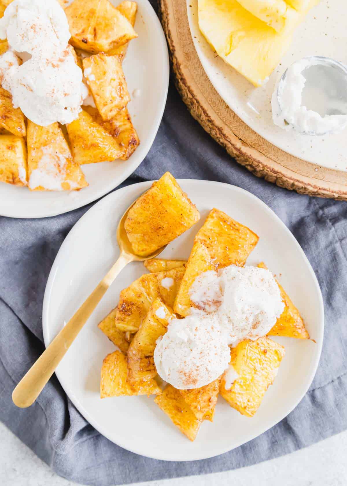 Air fryer roasted pineapple served with vanilla ice cream on plates.