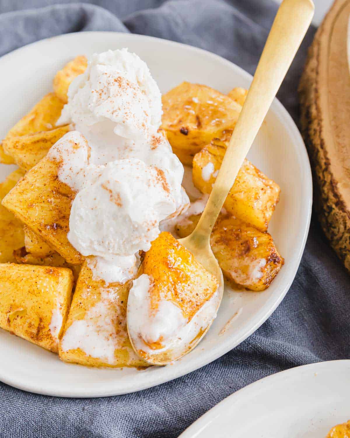 Close up of caramelized air fryer pineapple on a plate with ice cream and cinnamon dusting.