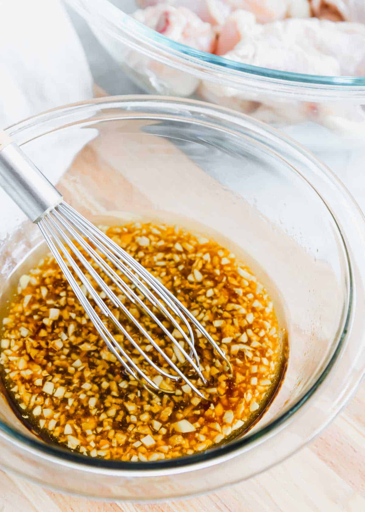 Chicken wing marinade in a glass bowl with a wire whisk.