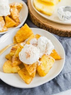 Air fryer pineapple with vanilla ice cream and dusting of cinnamon on a white plate.