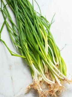 Bunch of green onions on a white surface.