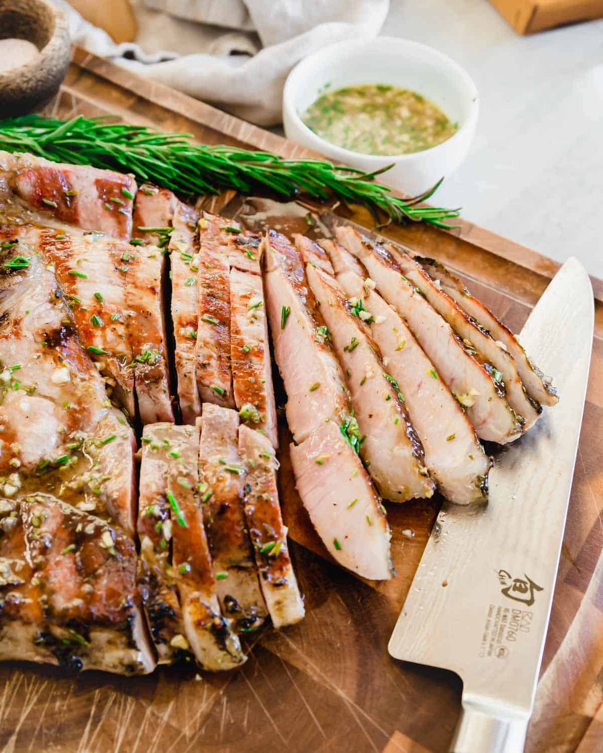 Sliced grilled ham steak with rosemary glaze on a cutting board.