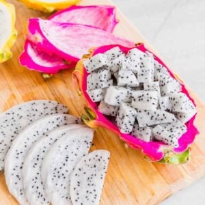 Dragonfruit cut into slices and cubes on a cutting board.