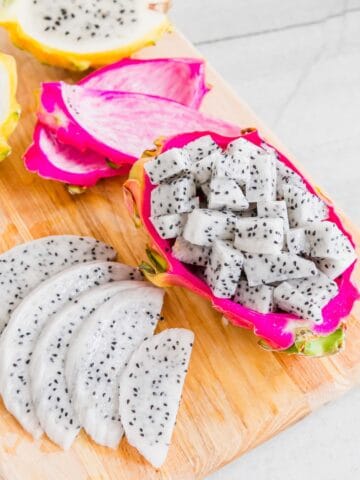 Dragonfruit cut into slices and cubes on a cutting board.