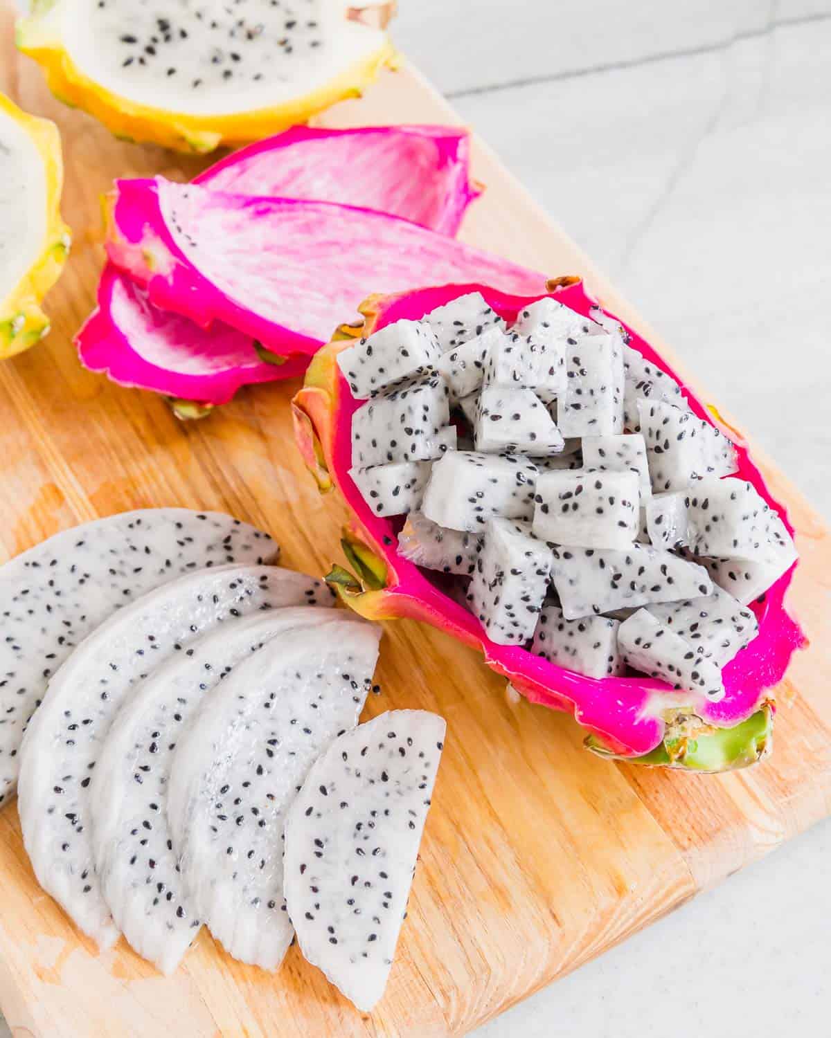 Dragonfruit cut into slices and cubes on a cutting board.