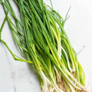 Bunch of green onions on a white surface.