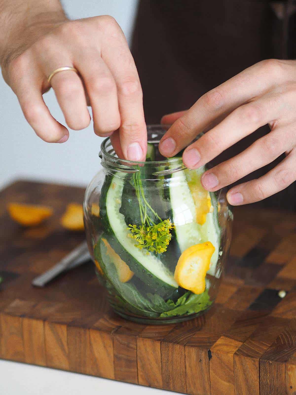 Quick pickling cucumbers and squash in glass jar.