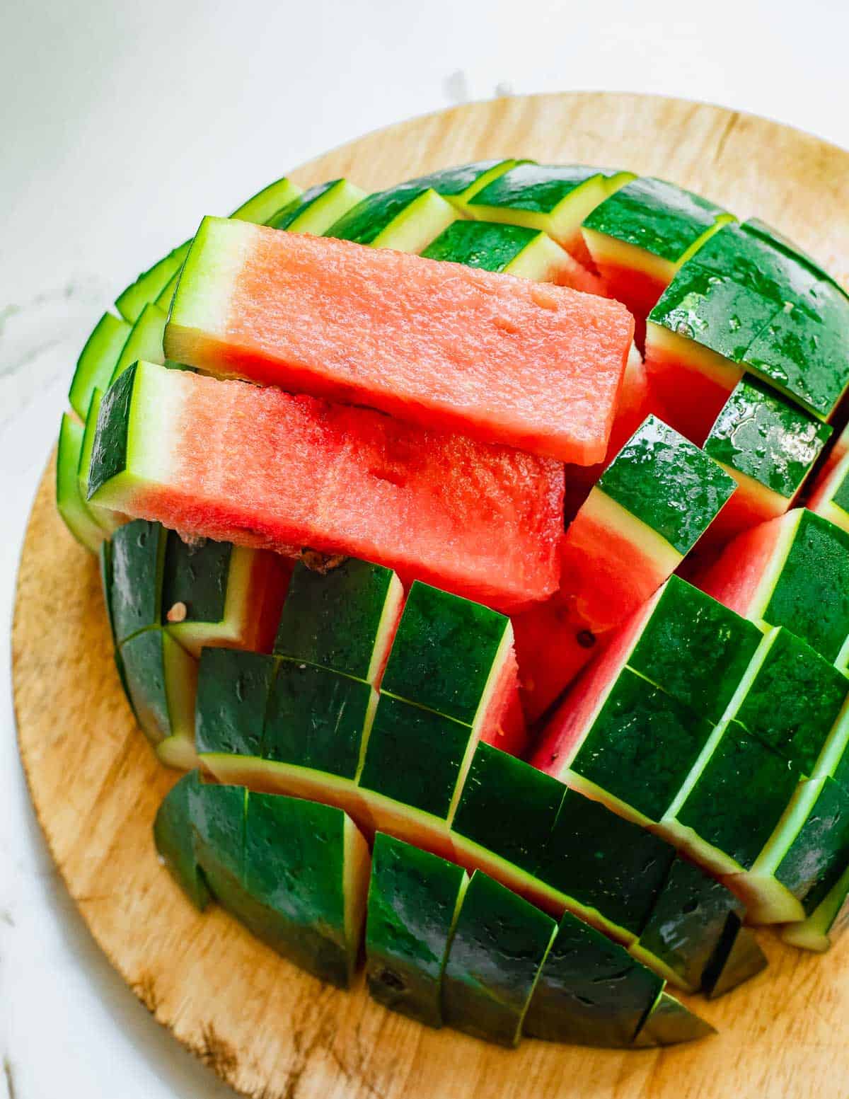 Two watermelon sticks sitting on top of a cut watermelon half.