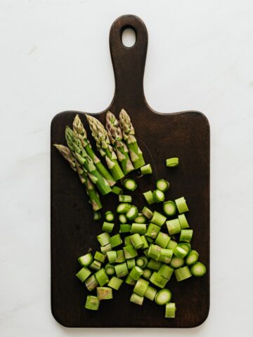 Asparagus ends chopped on a cutting board.