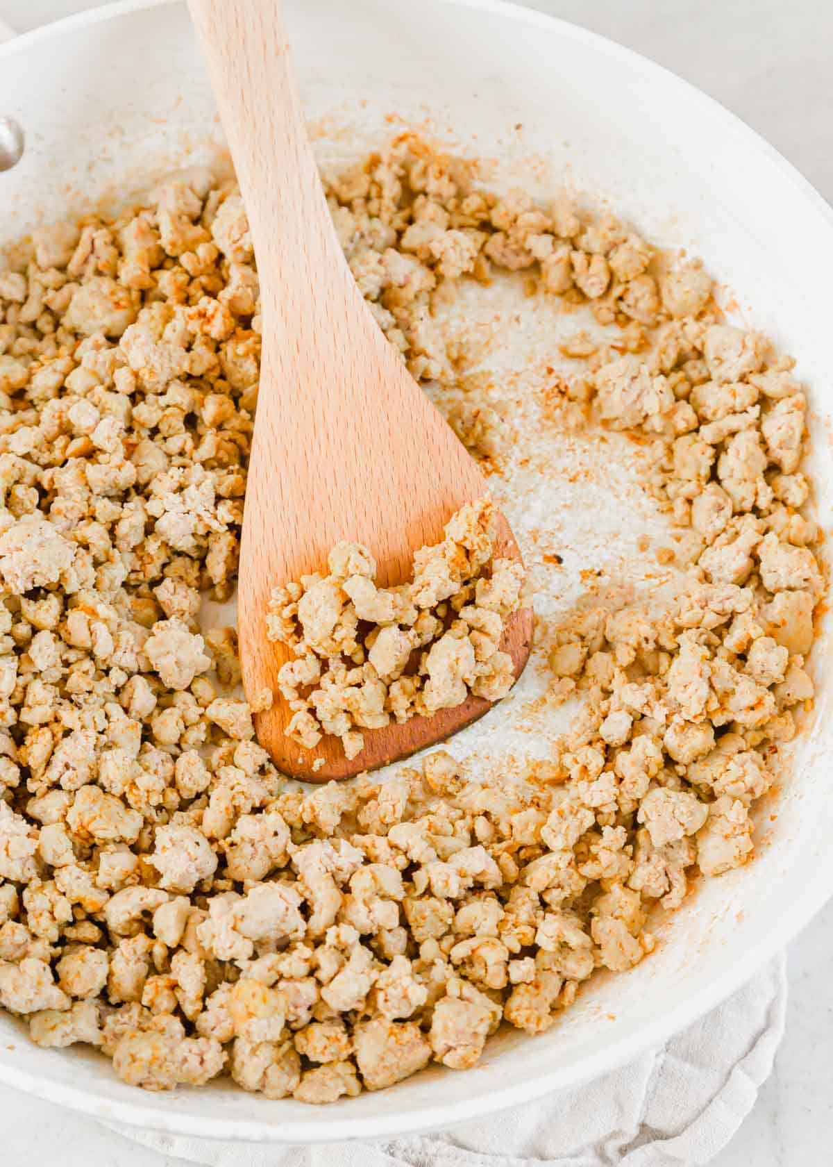 Fully cooked seasoned ground turkey meat in a skillet with a spatula.