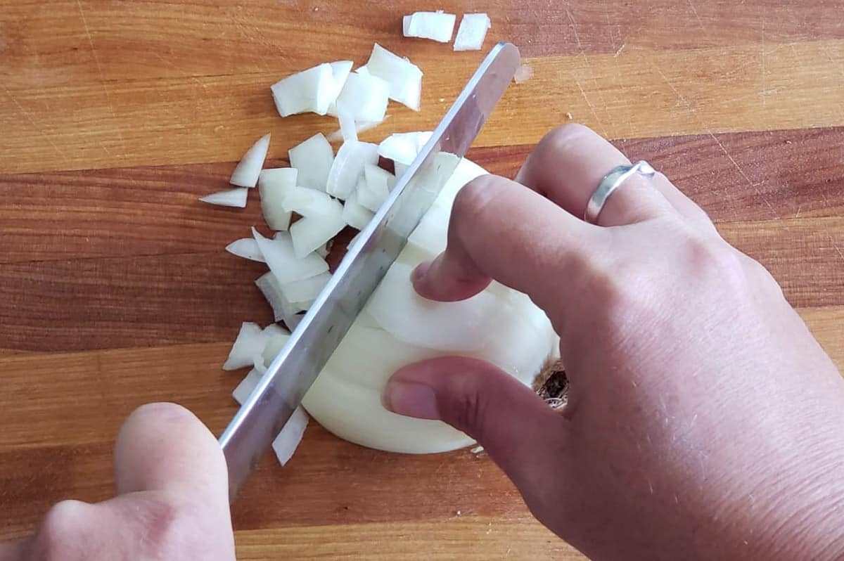 Dicing an onion on a cutting board.