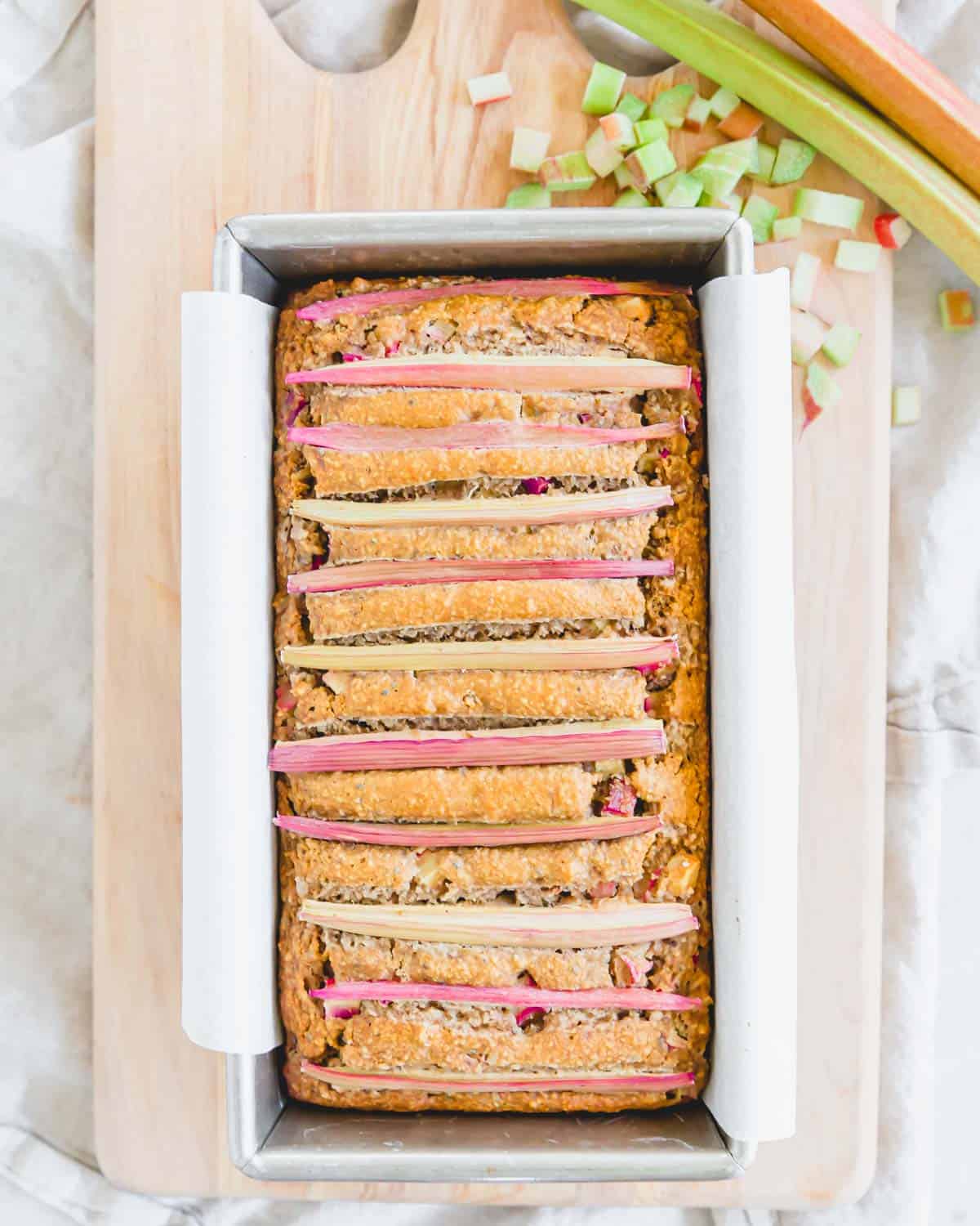 Baked gluten free rhubarb bread in a loaf pan with parchment paper.