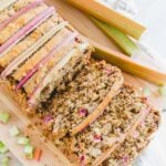 Loaf of rhubarb bread on a cutting board with three slices cut.
