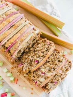 Loaf of rhubarb bread on a cutting board with three slices cut.