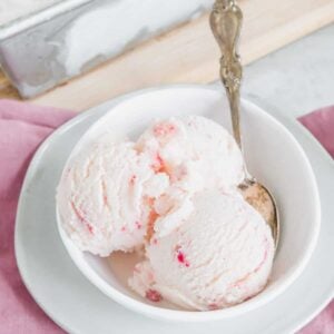 Strawberry vanilla kefir ice cream in a white bowl with a spoon.