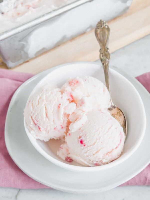 Strawberry vanilla kefir ice cream in a white bowl with a spoon.