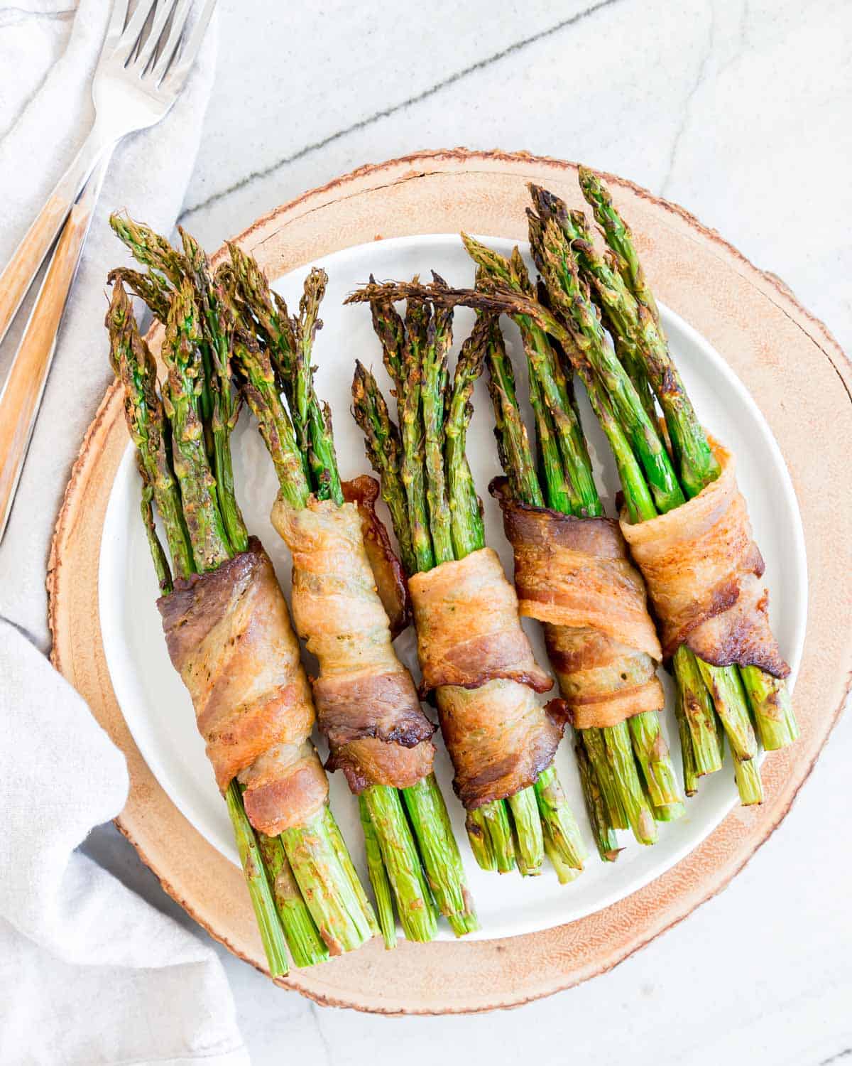 Bacon wrapped asparagus on a white plate.