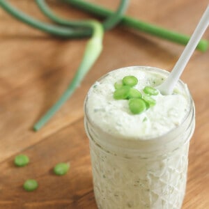 Garlic scape pesto in a jar with a white spoon.