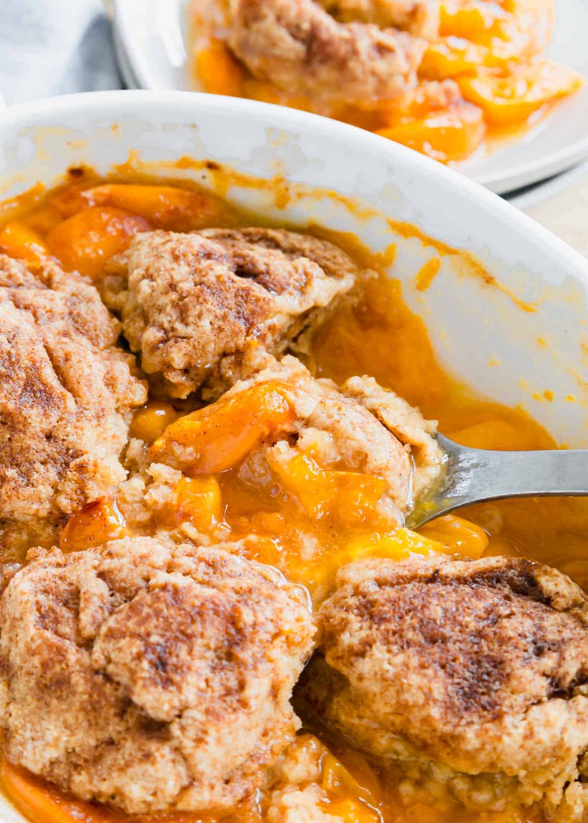 Close up of serving spoon in apricot cobbler.