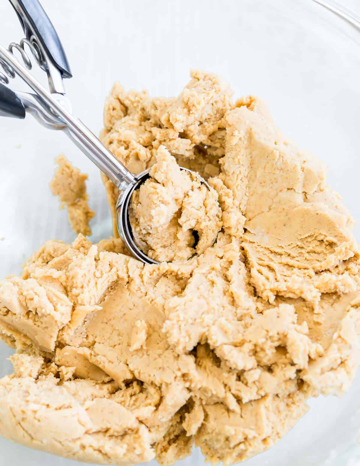 Cookie scoop in a bowl with peanut butter cookie dough.
