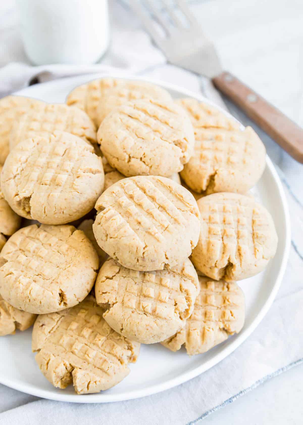 Criss cross gluten-free peanut butter cookies piled on a plate.