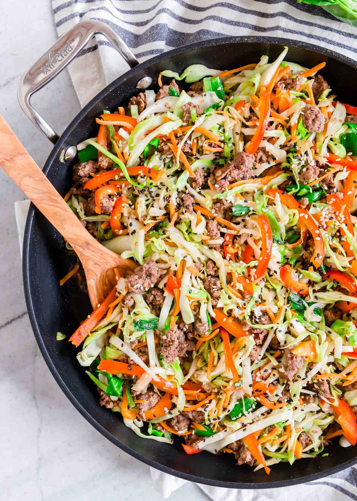 Ground beef cabbage skillet in a pan with a wooden serving spoon.