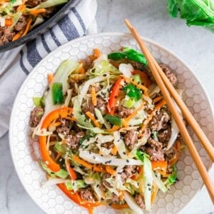 Ground beef cabbage stir fry in a bowl with chopsticks resting on the side.