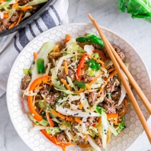 Ground beef cabbage stir fry in a bowl with chopsticks resting on the side.