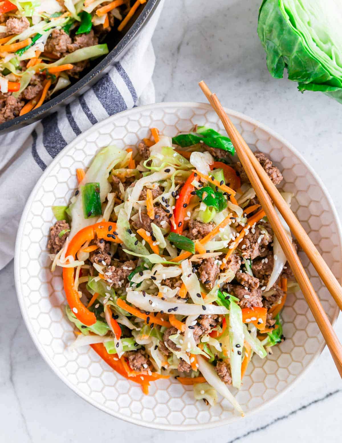 Ground beef cabbage stir fry in a bowl with chopsticks resting on the side.