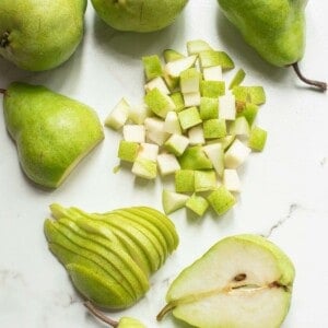 Chopped, sliced and halved pears on a white surface.