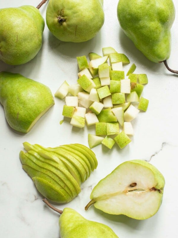 Chopped, sliced and halved pears on a white surface.