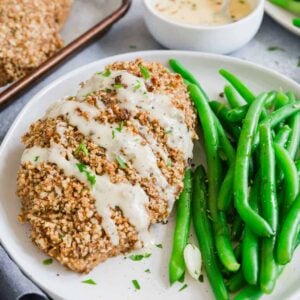 Pecan crusted chicken with honey dijon sauce drizzled on top on a plate.